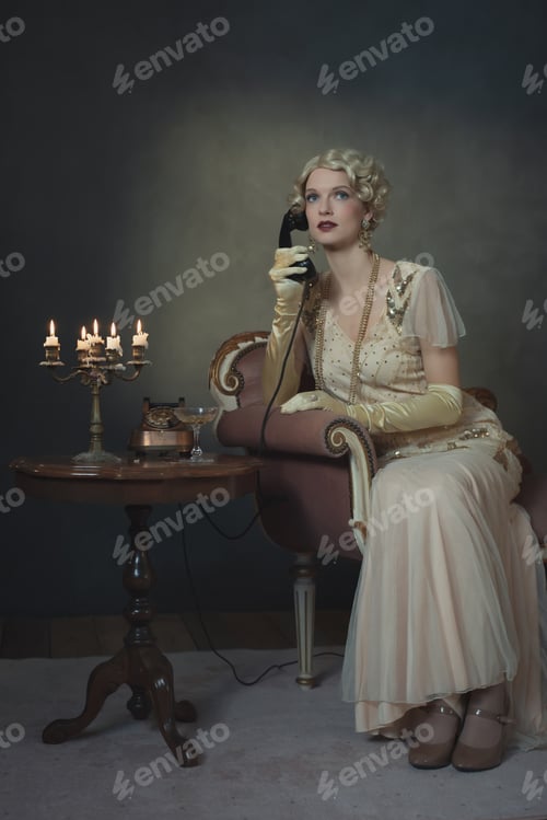 Preview: Retro 1920S Fashion Woman On The Phone While Sitting On Sofa Beside Table With Candlestick And