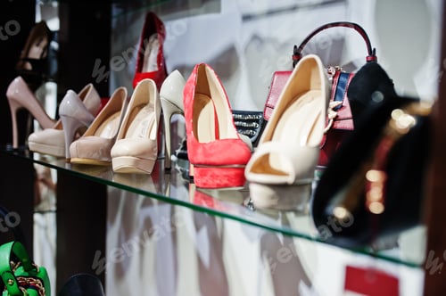 Preview: Huge variety of female shoes and bags of different colors on the shelves of the shop.