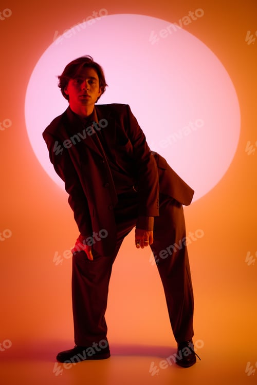 Preview: Stylish young man poses creatively against vibrant circular background in modern setting