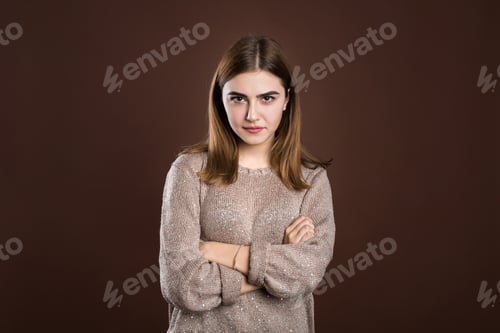Preview: Girl frowning her face in displeasure, wearing loose long-sleeved sweater, keeping arms folded.
