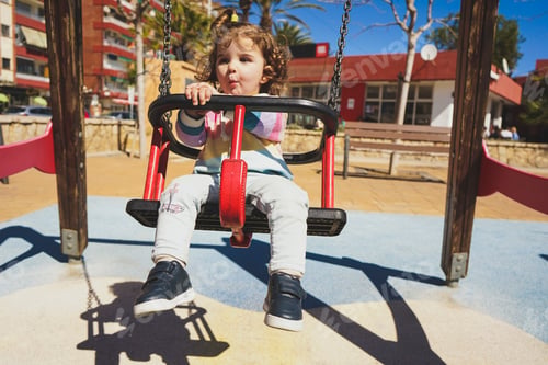 Preview: Young little girl playing in a swing at the park