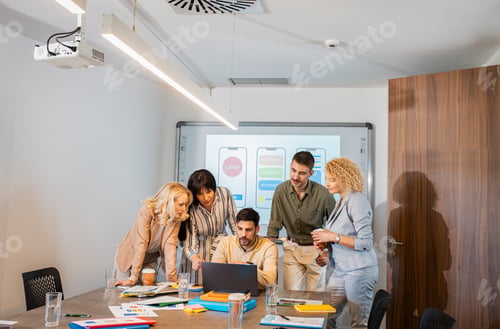 Preview: Group of business people sitting in a meeting room discussing a design for a smartphone application.