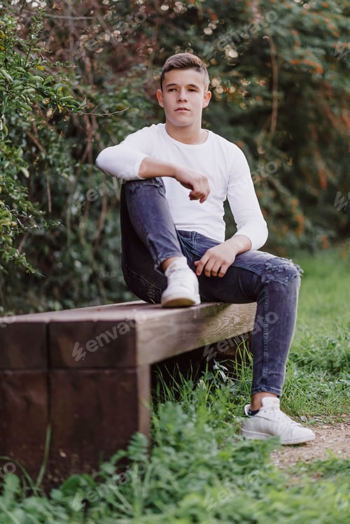 Preview: Portrait of a teenager sitting on a park bench, looking camera.
