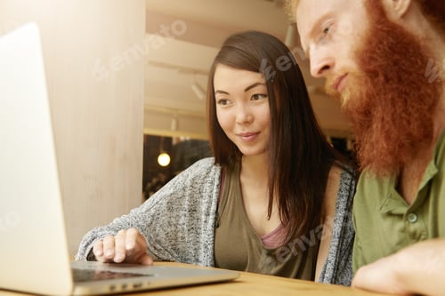 Preview: Portrait of two students using laptop while having lunch after classes at college: smiling pretty gi