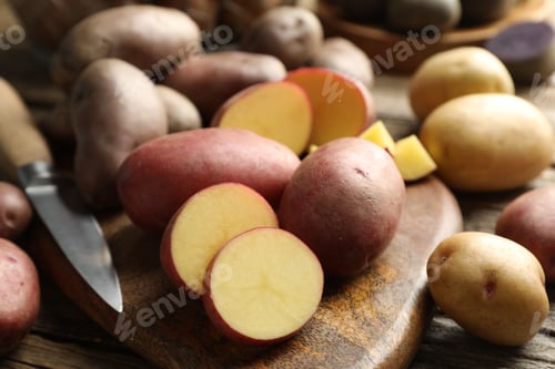 Preview: Different types of potatoes and knife on wooden table, closeup
