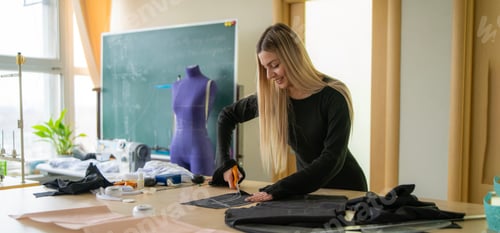 Preview: A seamstress skillfully cuts fabric on a table