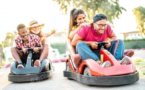 Preview: Milenial friends having fun at children playground on go kart race