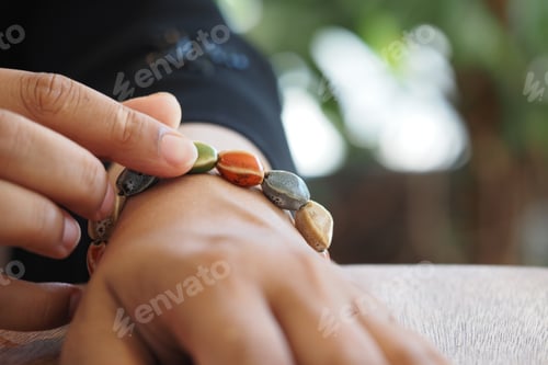 Preview: Hand adjusting colorful stone bracelet in a sunny setting