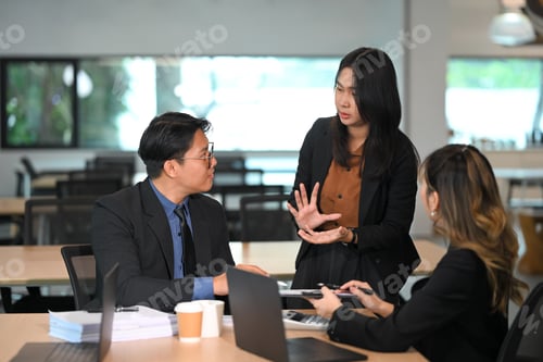 Preview: Female team leader explaining project strategy to colleagues in a modern meeting room