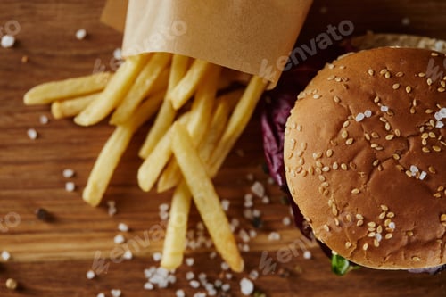 Preview: top view of salt, french fries and delicious burger on wooden surface
