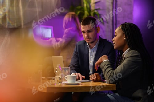 Preview: Two business people having a meeting in a cafe while using a laptop