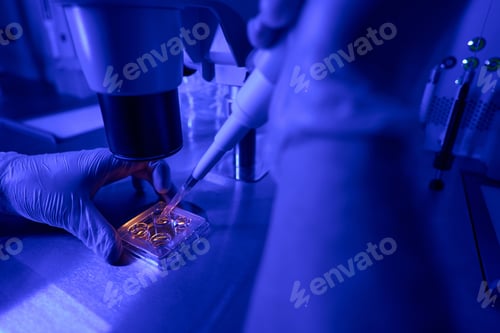 Preview: Laboratory worker adding special fluid to plate with embryo samples