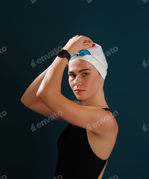 Preview: Portrait of a young professional female swimmer looking at the camera against blue background