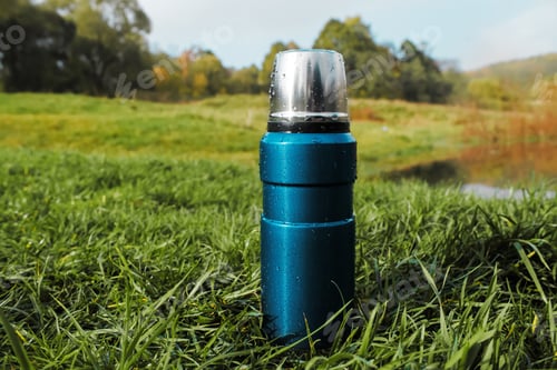 Preview: Steel vacuum thermos on a forest background. Blue Travel Flask