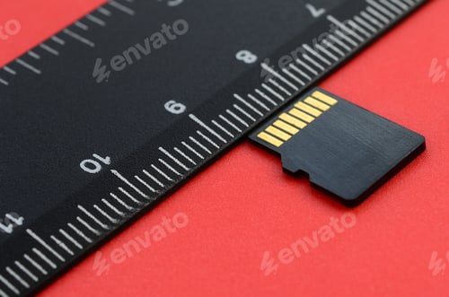 Preview: Small micro SD memory card lie on a red background next to a black ruler