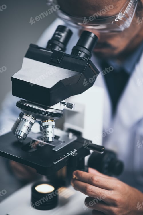 Preview: Young scientist looking through a microscope in a laboratory. Young scientist doing some research.