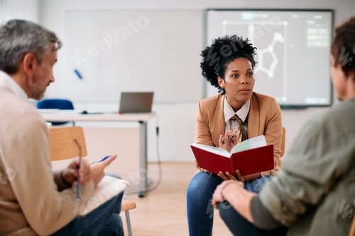 Preview: Black female professor having consultations with adult students at lecture hall.