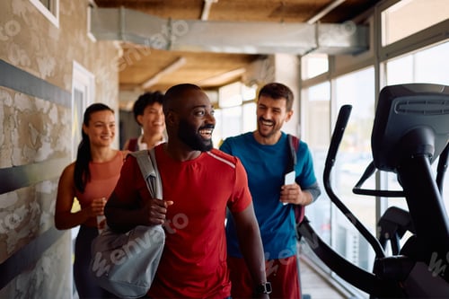 Preview: Happy black athlete and his friends coming to sports training in a gym.