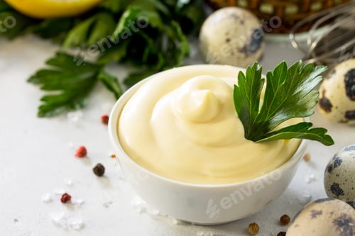 Preview: Homemade mayonnaise sauce in a white bowl on a light stone table.