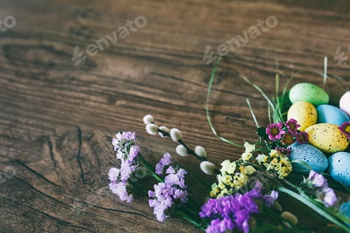 Preview: Easter background. Bright colorful eggs in nest with spring flowers over wooden dark background