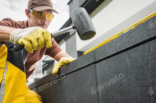 Preview: Construction Worker Using a Hammer to Align Blocks While Building a Structure Outdoors
