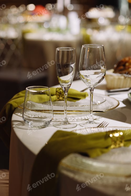Preview: Empty wine glasses on table with green napkins in restaurant interior