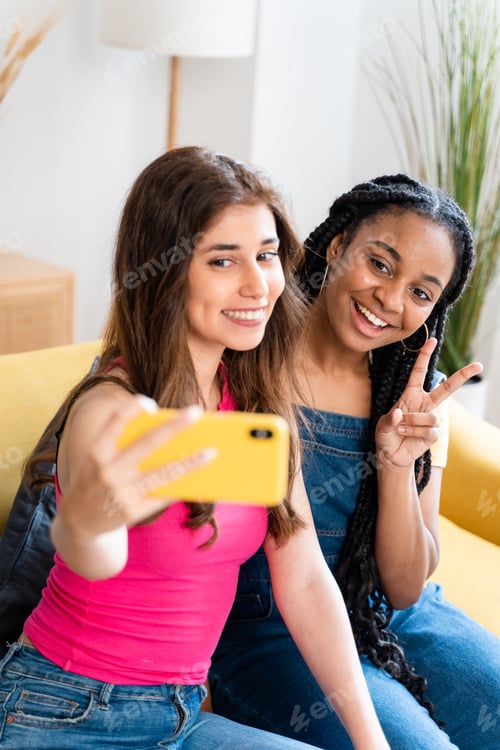 Preview: Happy female friends taking a selfie at home.