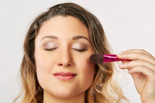 Preview: Young woman using blusher brush