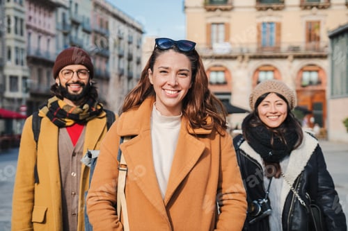 Preview: Group of young people looking at camera on european city street. Portrait of three cheerful