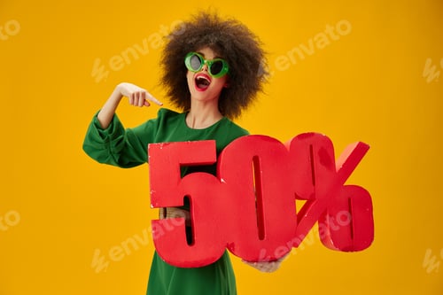 Preview: Beautiful fashionable girl green dress afro hairstyle dark glasses fifty percent in hands yellow