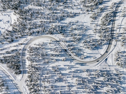 Preview: Aerial view of snowy and frozen winter road. Winter landscape with snow covered trees in Finland.
