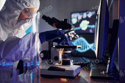 Preview: Side view of scientist in white protective uniform that works with coronavirus in laboratory