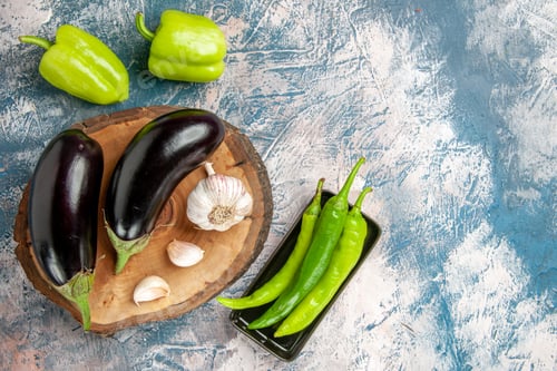 Preview: front view aubergines garlic on tree wood board peppers hot green peppers on black plate on
