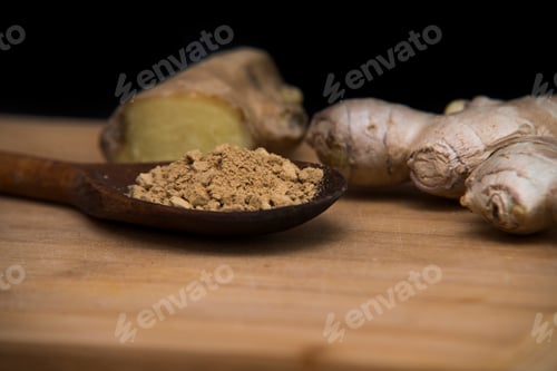 Preview: close up on fresh ginger and powder on wood with black background
