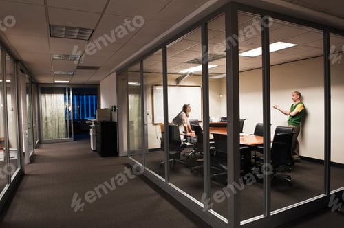 Preview: Caucasian man and woman working after hours in an office conference room.