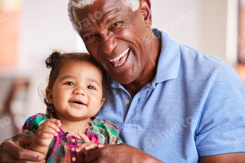 Preview: Portrait Of Smiling Grandfather Sitting On Sofa At Home With Baby Granddaughter
