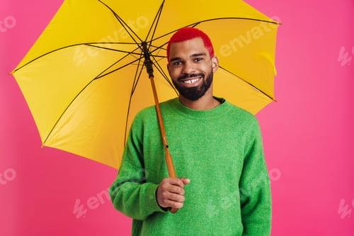 Preview: Joyful african american guy smiling while posing with umbrella