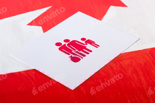 Preview: selective focus of white card with family icon on canadian flag, immigration concept
