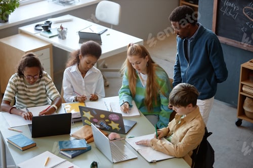 Preview: Group of Kids Working at Big Table in Class with Male Teacher Watching