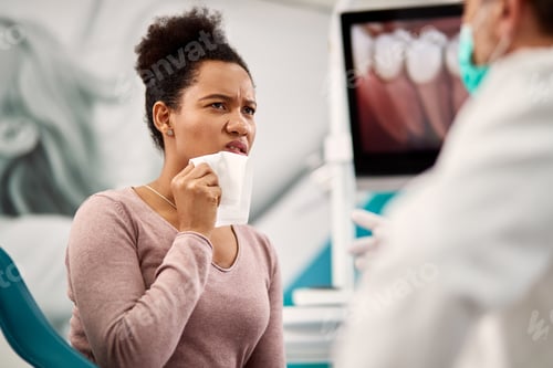 Preview: Displeased black woman with toothache talking to a dentist during appointment at dental clinic.