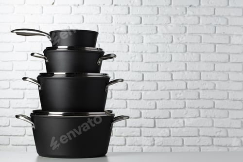 Preview: Set of cookware on table against white brick wall