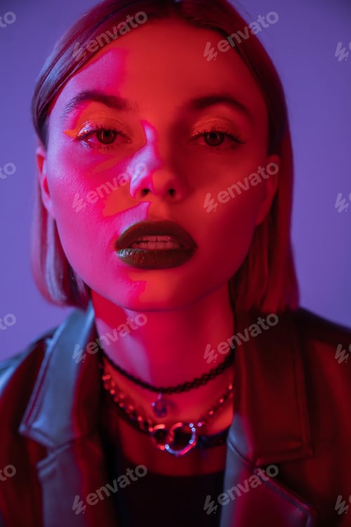 Preview: portrait of woman in bright makeup looking at camera in red light isolated on purple