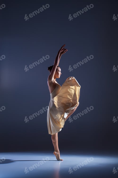 Preview: Young Beautiful Dancer In Beige Dress Dancing On Gray Studio Background