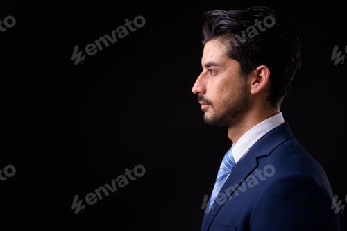 Preview: Young handsome bearded Persian businessman against black background