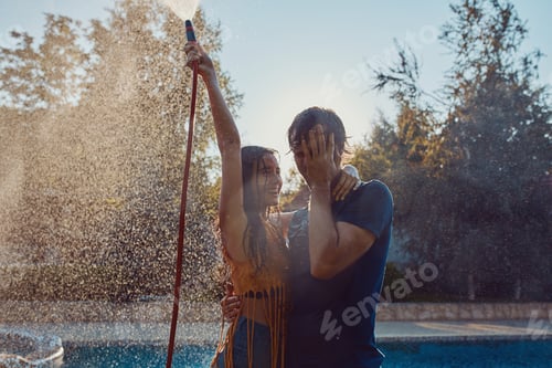 Preview: Couple having fun pour each other with garden hose