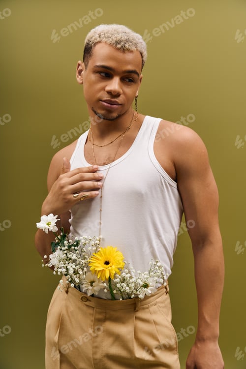 Preview: Young man showcasing trendy style with flowers in a vibrant studio setting
