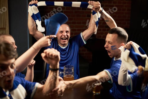 Preview: Group of Diverse Young Male Fans Celebrating Soccer Match Victory Indoors
