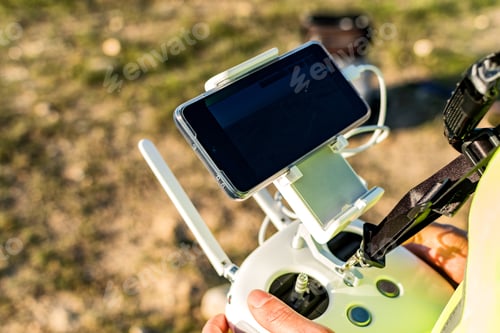 Preview: Shallow focus of male hands holding a remote controller of a drone on blurred background of a field