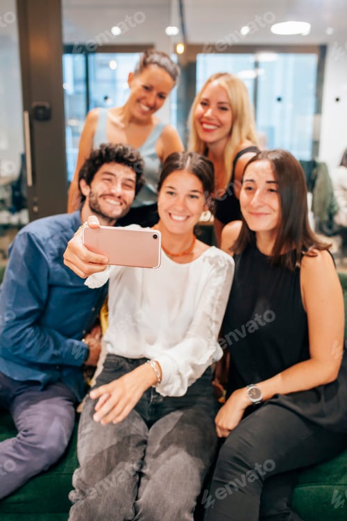 Preview: Cheerful group of coworkers taking selfie on smartphone