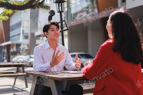 Preview: Young businessman discussing ideas with colleague outdoors